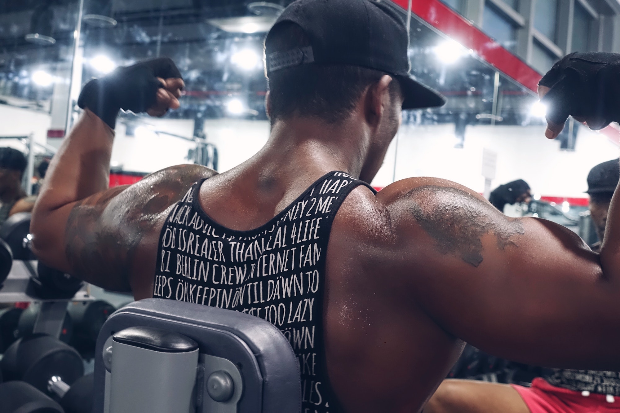 black man with tattoos flexing muscles at the gym - Tatuaż a siłownia - kiedy można przed i po zrobieniu